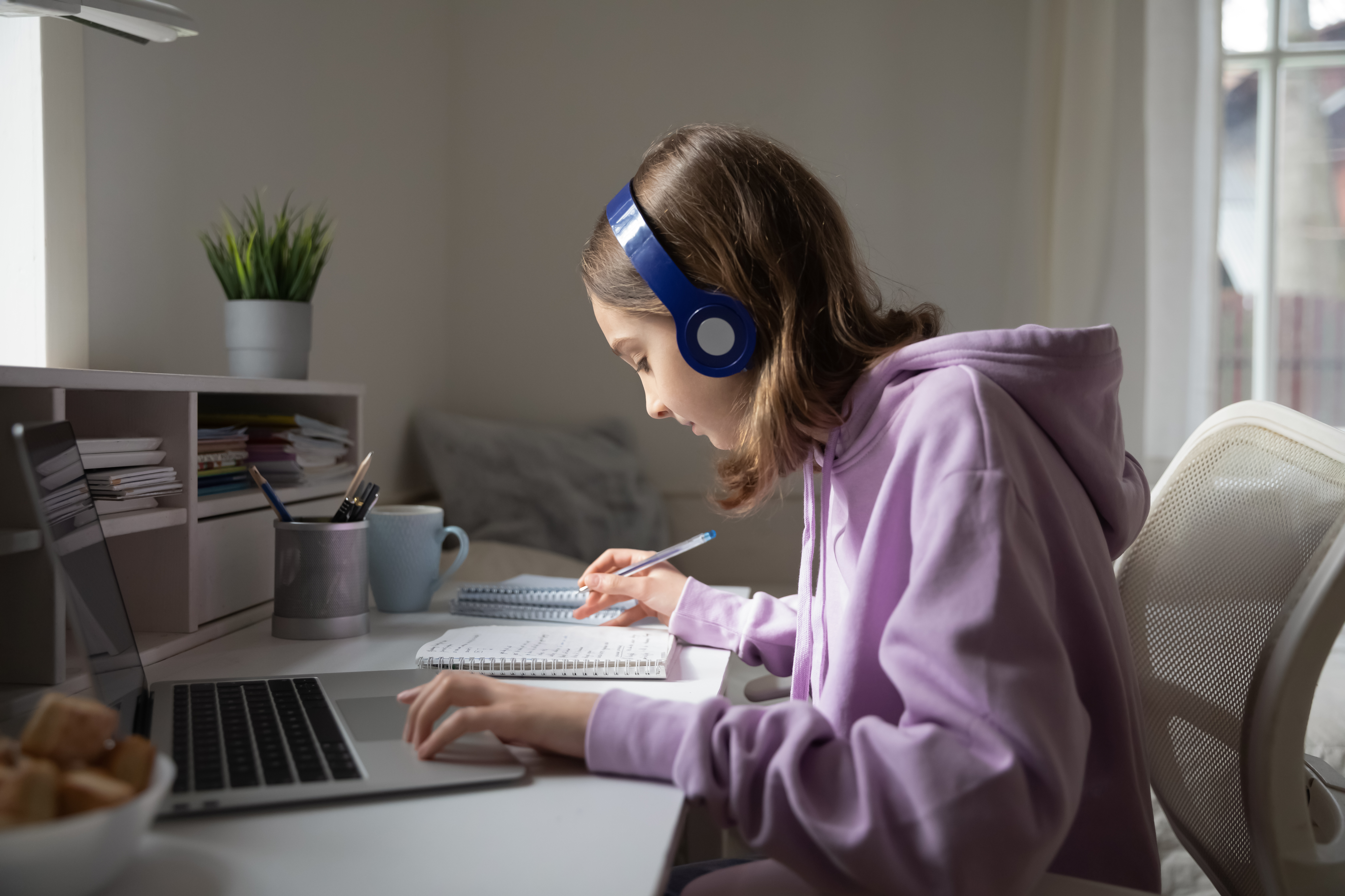 teen wearing headphones and studying online from home